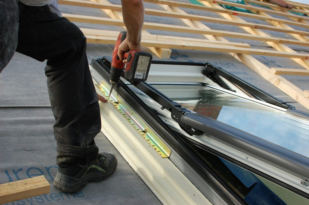assembling a sky light with screws on a roof with a cordless screwdriver